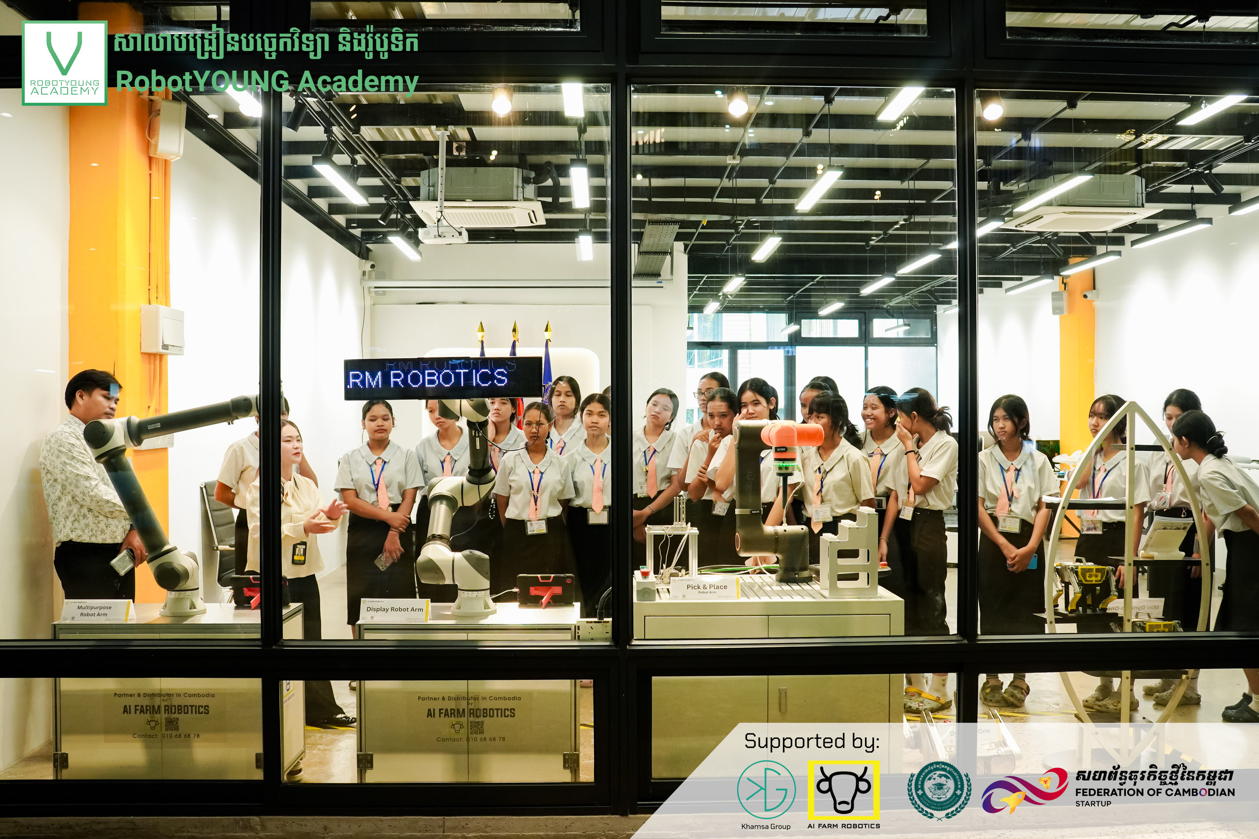 Students gathered around industrial robotics equipment in a workshop
