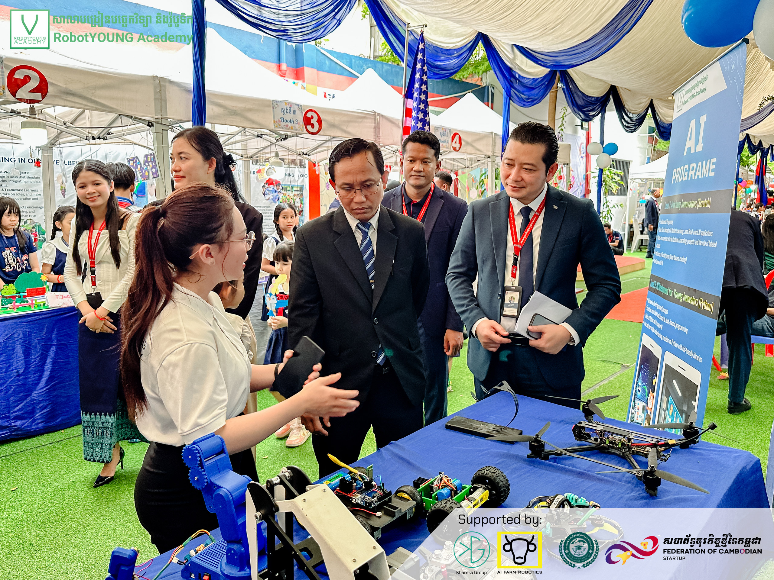 An exhibitor explaining robot models to visitors at a technology display table