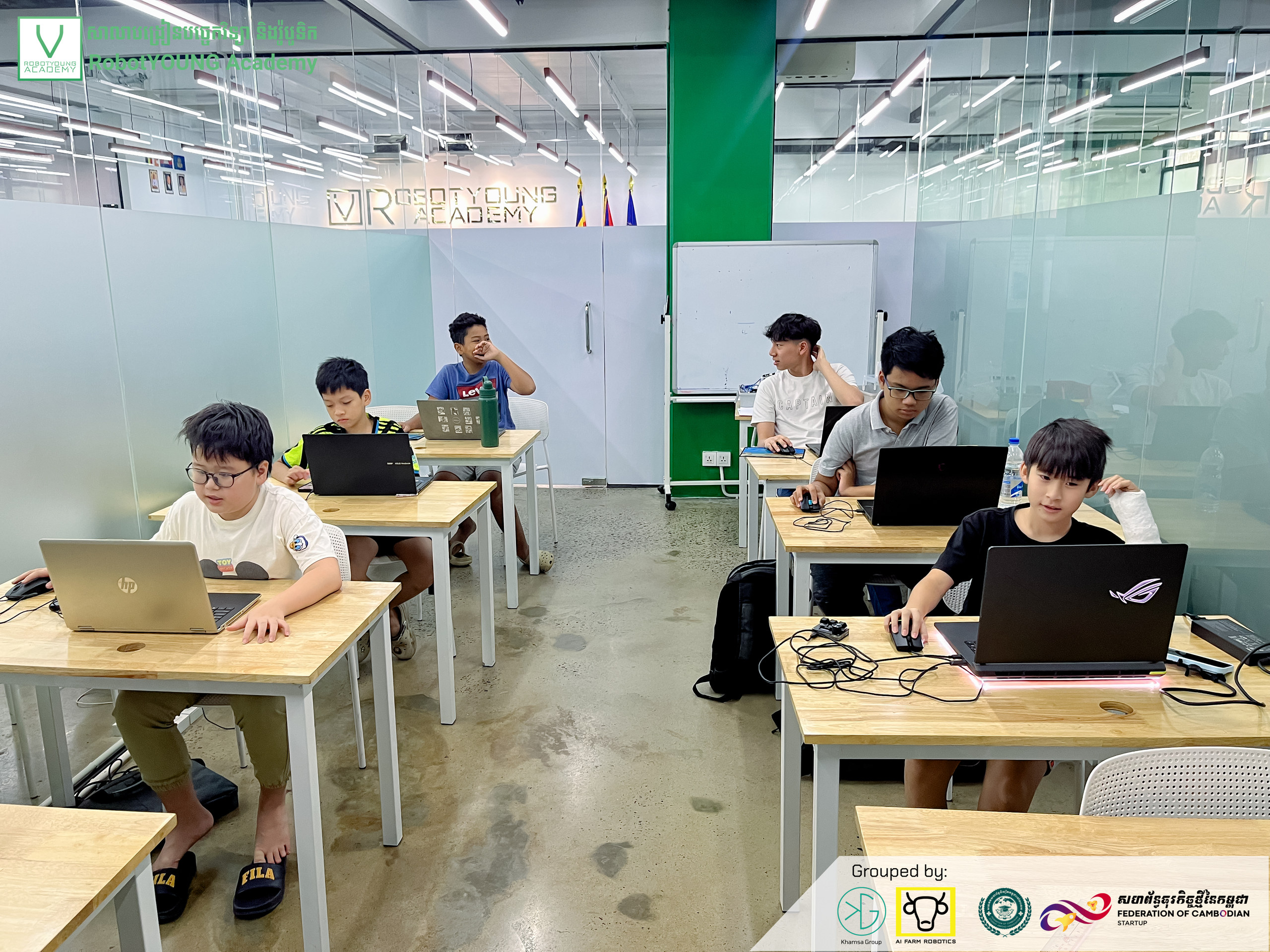 Learners working on laptops at individual tables in a robotics classroom
